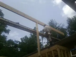 Carpenter setting a ridge beam over a new addition frame — Ice Dam Removal by Roofing Brothers in Clay City