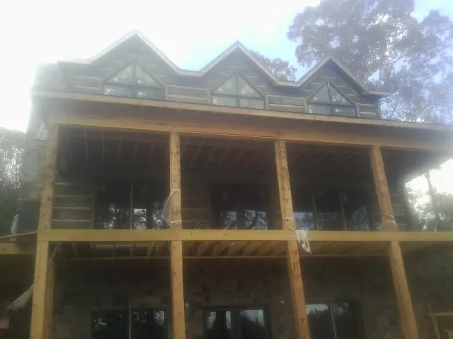 Dormers and porch framing on a large log home under construction — Roof Coating work by our crew in Clay City