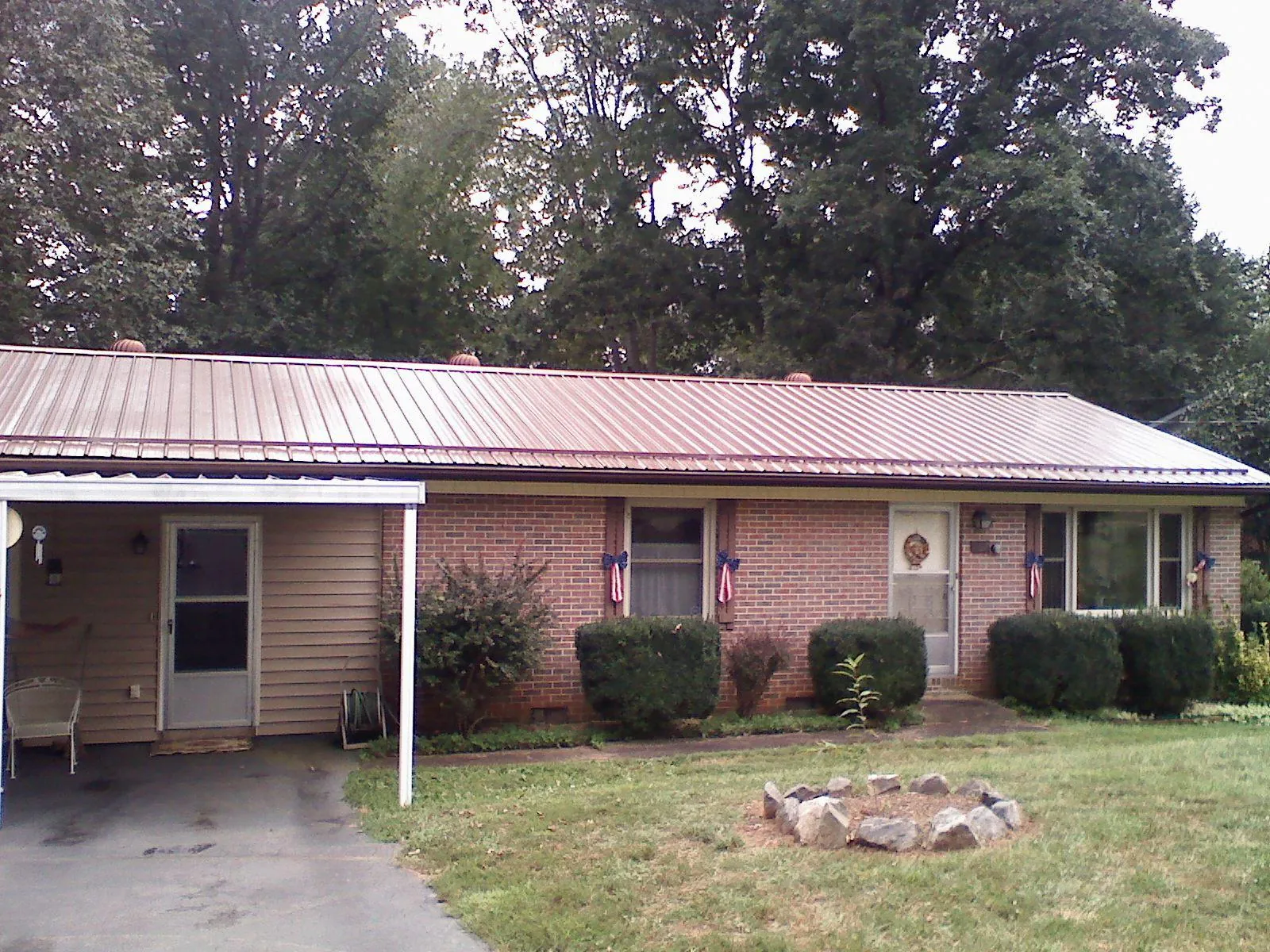 Bronze metal roof and carport on a brick ranch home — Roof Repair work by our crew in Clay City