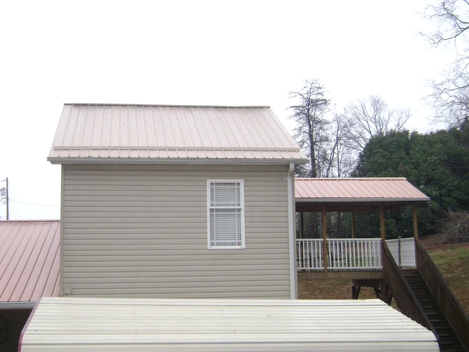 Tan metal roofs on a two story addition and attached porch, from a Roof Replacement job in Clay City
